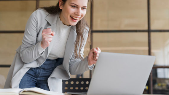 excited adult female looking at her laptop