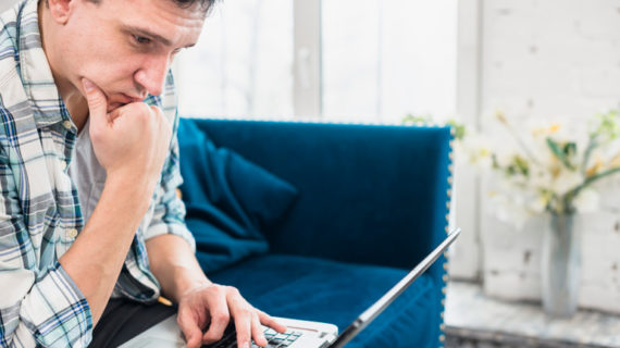 male thinking while looking at his laptop