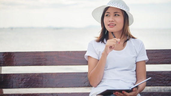 young happy woman thinking while writing