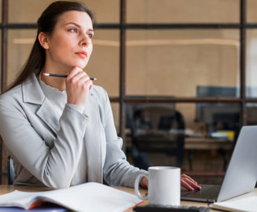 Contemplating businesswoman sitting in front of laptop