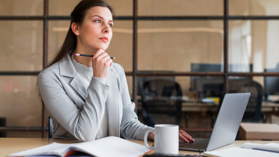 Contemplating businesswoman sitting in front of laptop