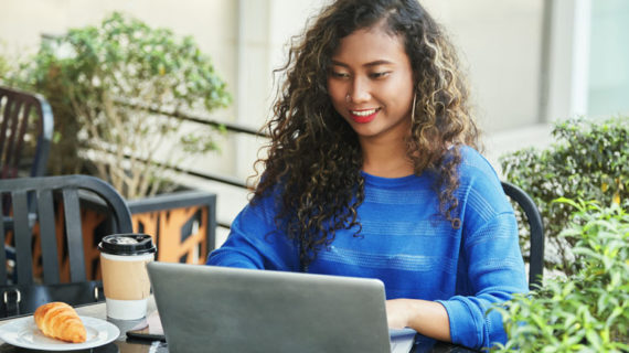 Smiling indonesian businesswoman browsing laptop