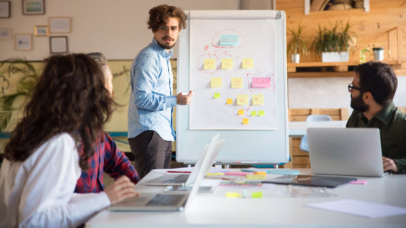 Startup leader drawing flowchart on board and discussing project