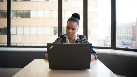 woman sitting on sofa facing laptop