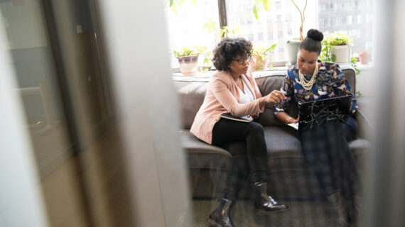 two woman sitting on gray couch