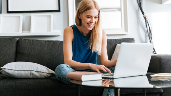 happy-woman-sitting-sofa-using-laptop-home