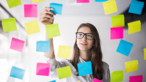 Young girl business woman in glasses watch on transperent wall