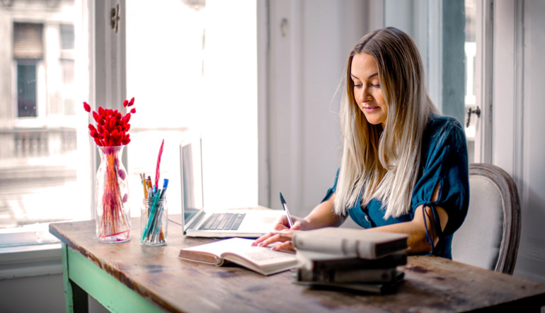 woman blue long-sleeve shirt sitting at the table working