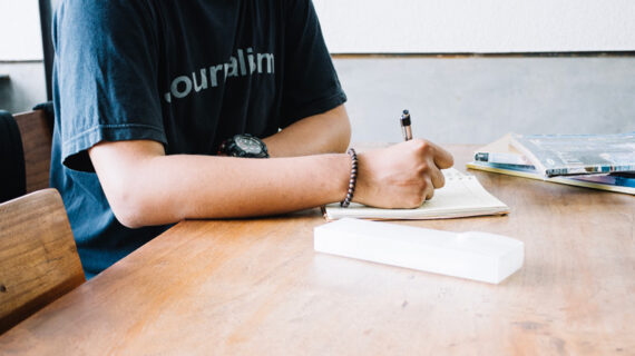 Crop man writing in notebook