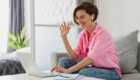 Attractive smiling woman in pink shirt sitting relaxed on sofa