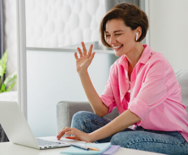 Attractive smiling woman in pink shirt sitting relaxed on sofa