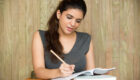 Portrait of smiling student writing in classroom