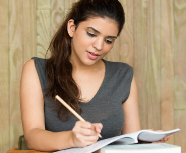 Portrait of smiling student writing in classroom