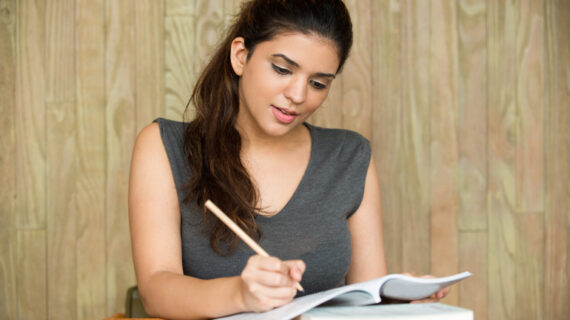 Portrait of smiling student writing in classroom