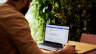 man in a brown jacket working using laptop