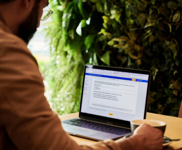 man in a brown jacket working using laptop