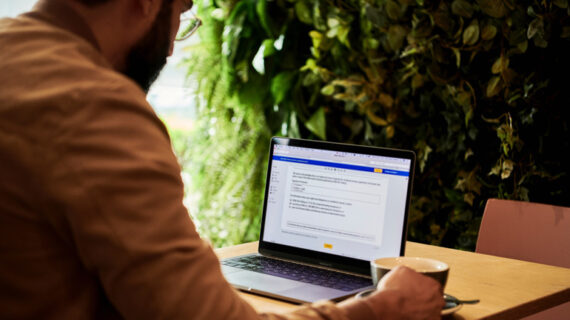 man in a brown jacket working using laptop