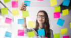 Young girl business woman in glasses watch on transperent wall